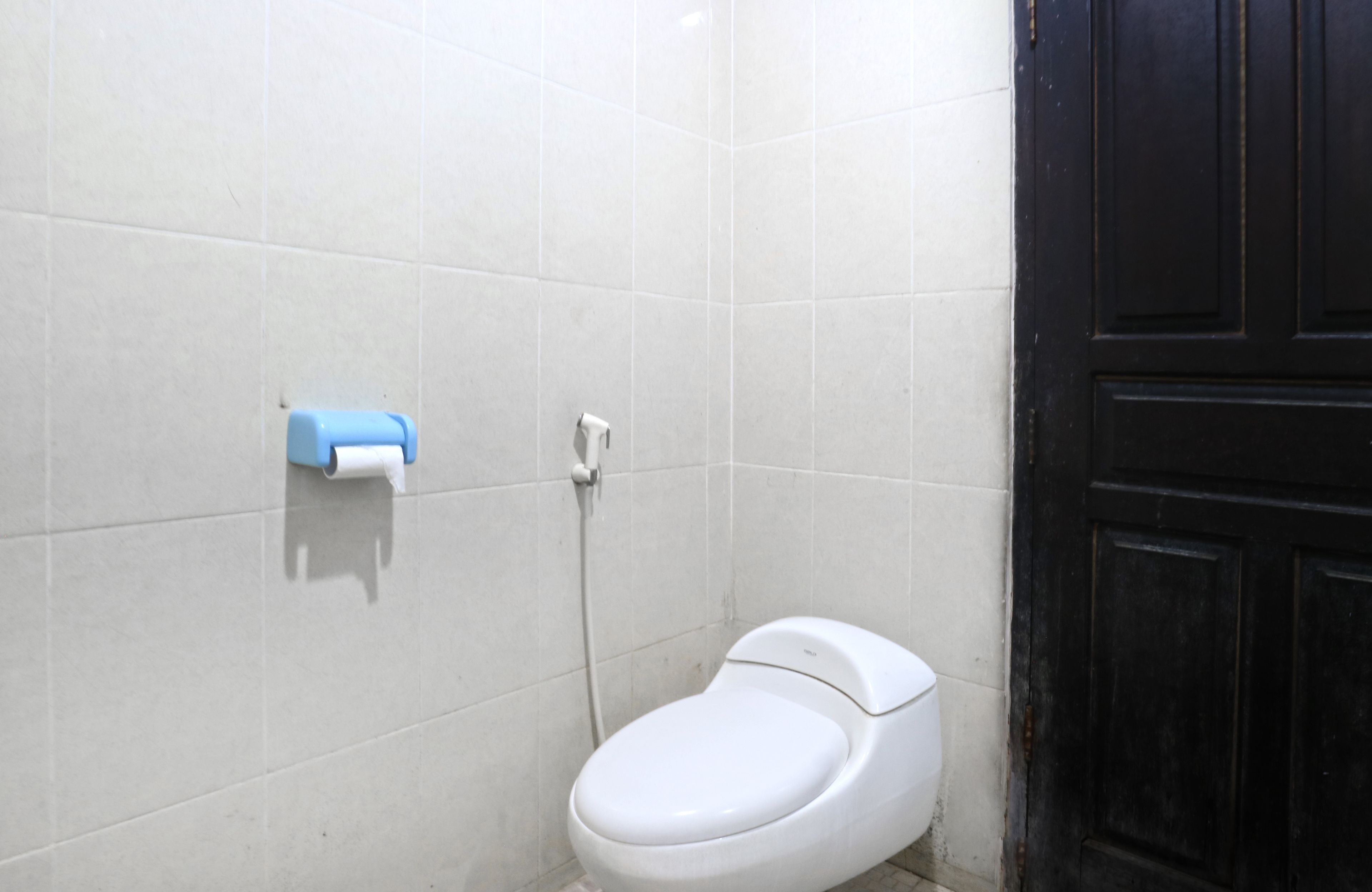Eine kleine, weiße Toilette mit einem blauen Papierhalter an der Wand.