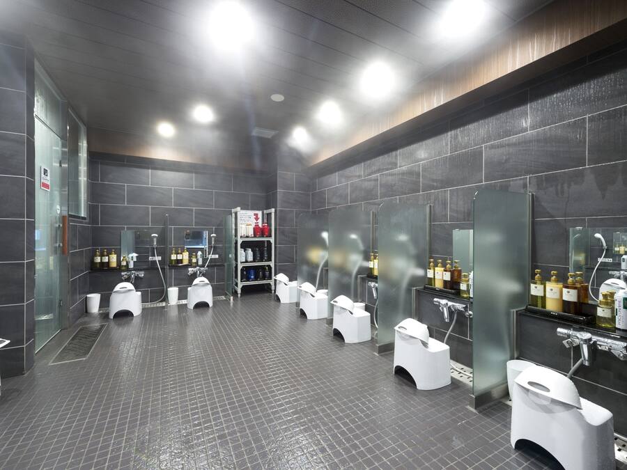 A modern restroom with multiple urinals and sinks, a tiled floor, and a glass partition wall.