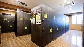 A row of dark wooden lockers with numbered signs, a wooden floor, and a ceiling with recessed lighting.