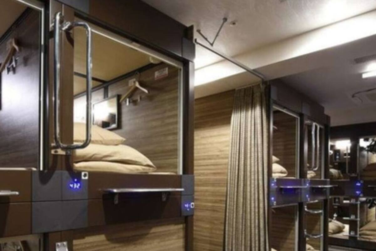 Habitación de hotel pequeña con literas, un escritorio y un espejo.