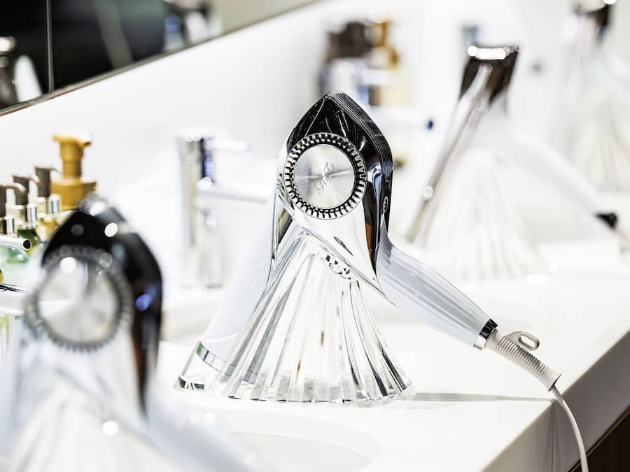 Un baño con un lavamanos moderno, un espejo y un secador de pelo.