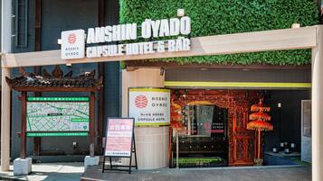 A hotel entrance with signage for 'Anshin Oyado Capsule Hotel & Bar,' a map, and a 'Woman Only' sign.