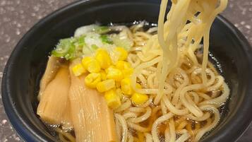 A bowl of ramen with noodles, corn, and vegetables.