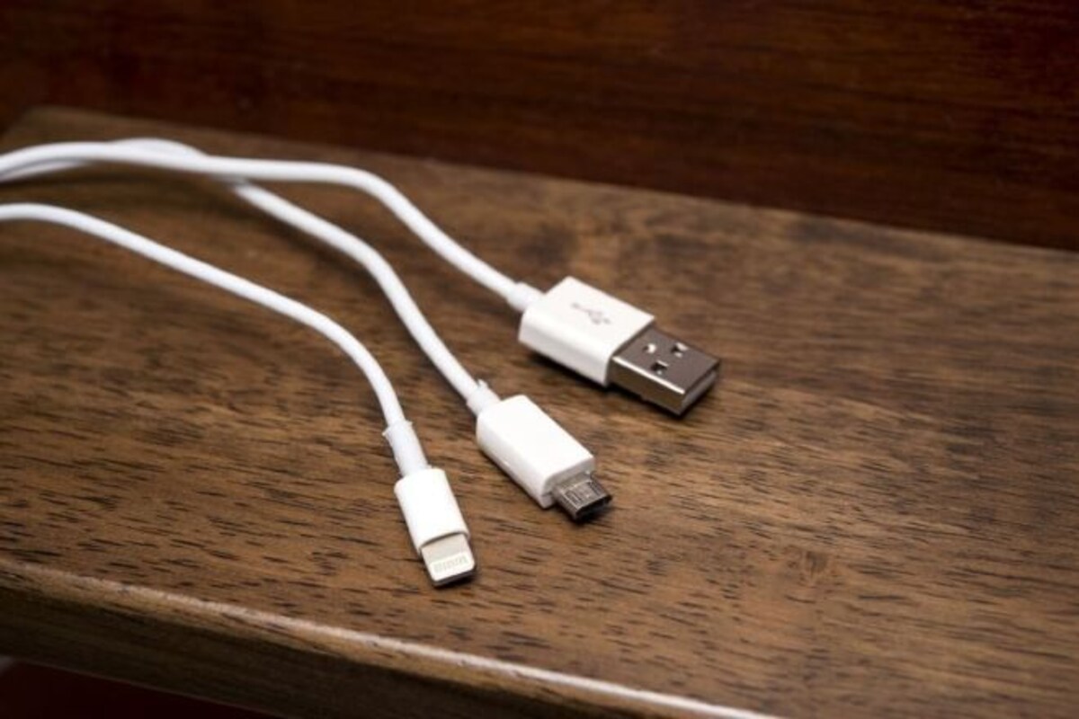 Un cable USB y un adaptador sobre una superficie de madera.