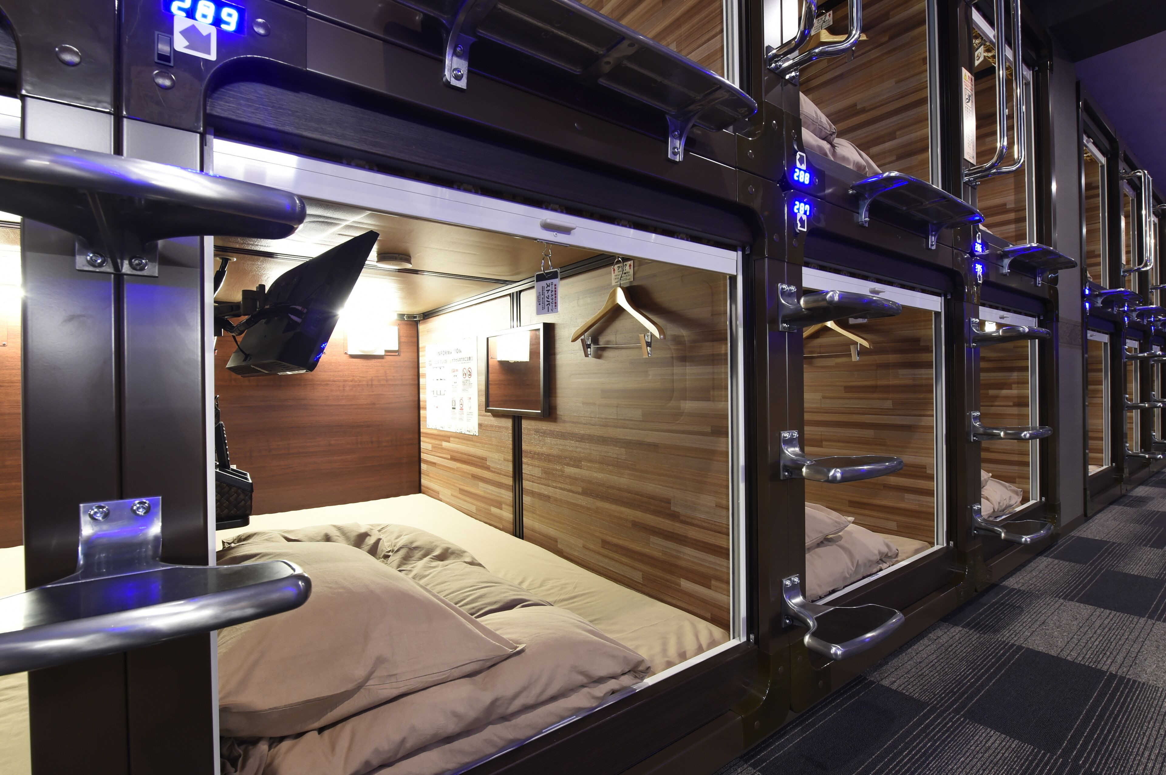 A train compartment with bunk beds, overhead luggage racks, and a wooden wall.