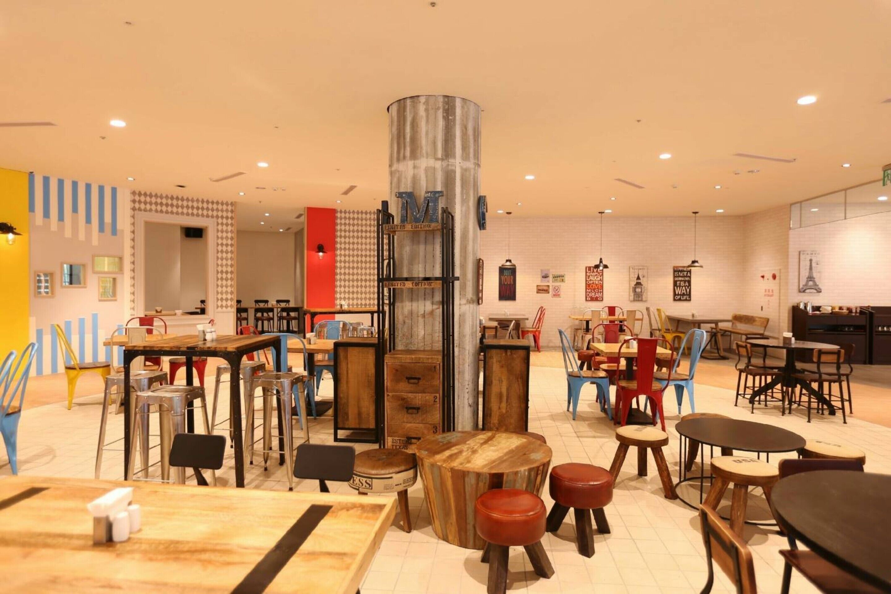 Un interior moderno con diversas opciones de asientos, incluyendo mesas y sillas, y una columna decorativa central.