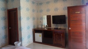 A bedroom with a wooden wardrobe, a television mounted on the wall, and a small refrigerator. - The Park Nangrong Resort (Nang Rong)