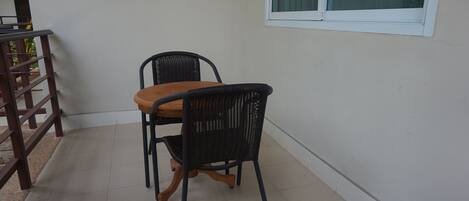 A small, enclosed patio area with a wooden table and two black wicker chairs.