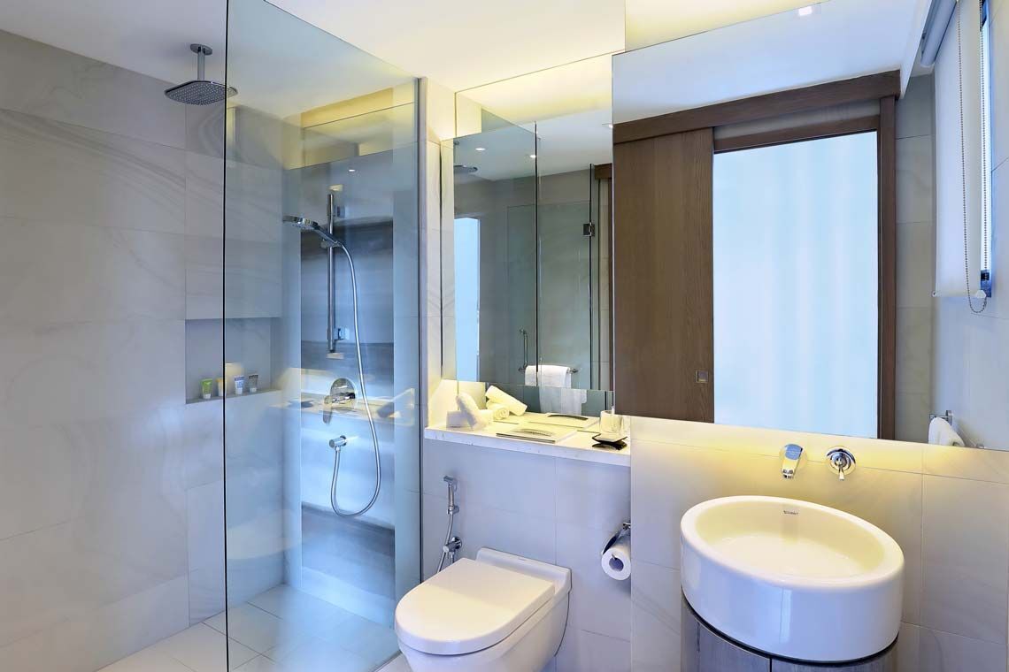 A modern bathroom with a glass shower enclosure, a toilet, and a sink.