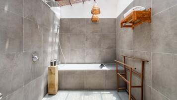 Un baño moderno con una bañera independiente, un perchero de madera y una lámpara colgante.