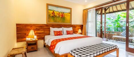 Un dormitorio con cabecera de madera, una cama grande con colcha roja y blanca, un banco al pie de la cama y un cuadro sobre la cama.