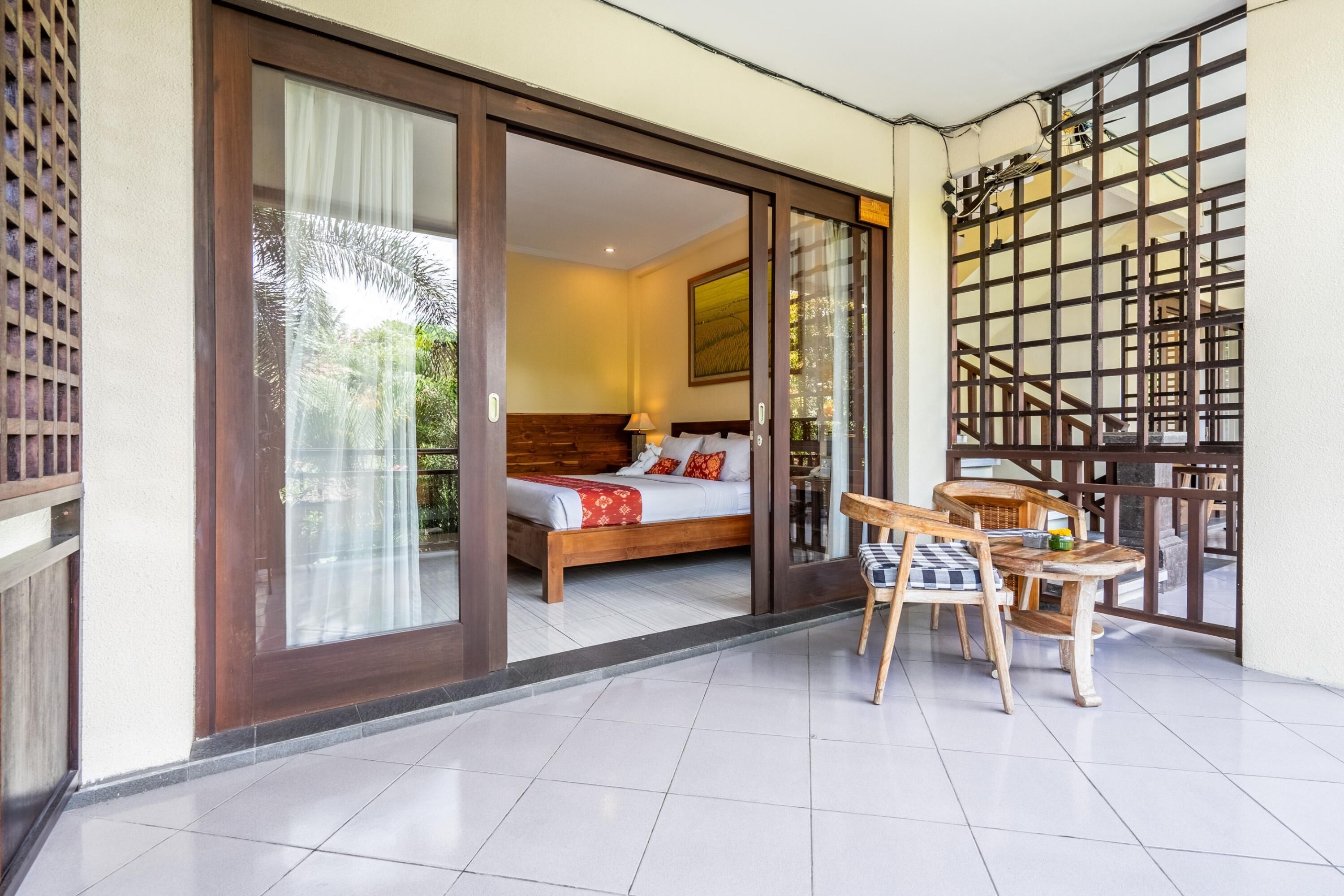 A hotel room with a bed, a table with chairs, and a view through a sliding door.