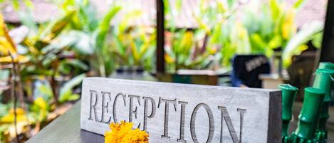 A reception sign with a flower on a wooden table.