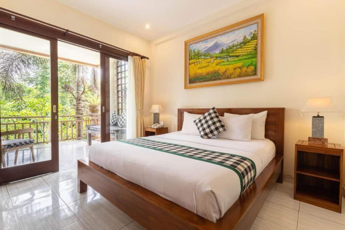 A bedroom with a large bed, a nightstand, a lamp, and a painting of a landscape.