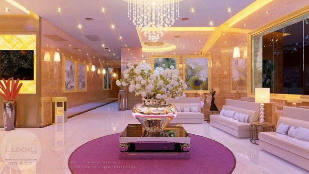 A luxurious lobby with a central seating area, a large chandelier, and artwork on the walls.