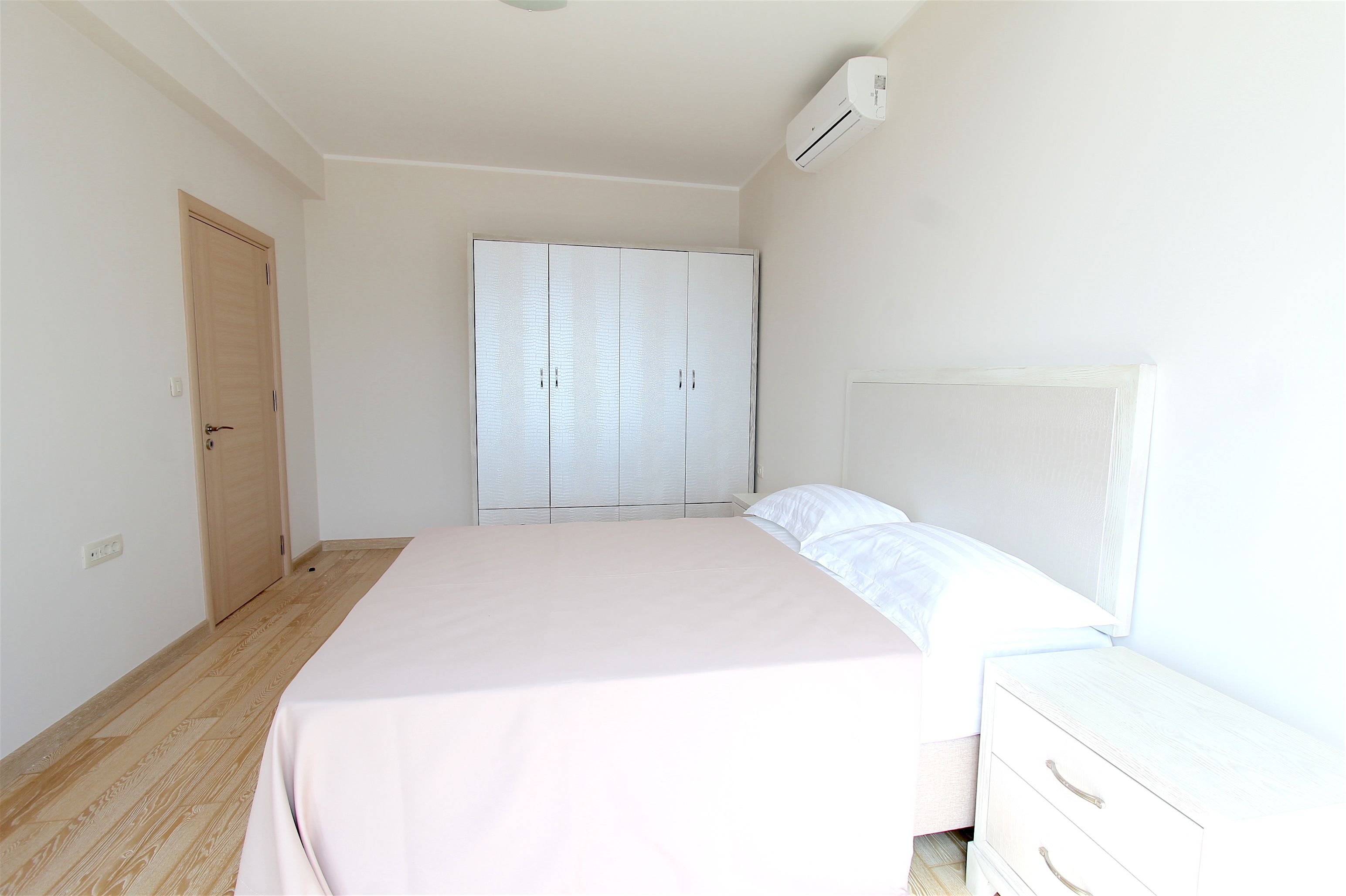 Un dormitorio con cama, armario y mesita de noche.