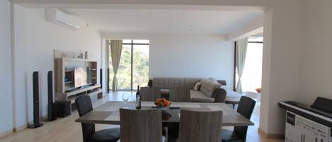 Una sala moderna con comedor, sofá y televisor.