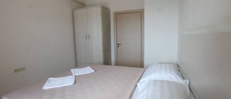 A bedroom with a bed, a wardrobe, and a door.