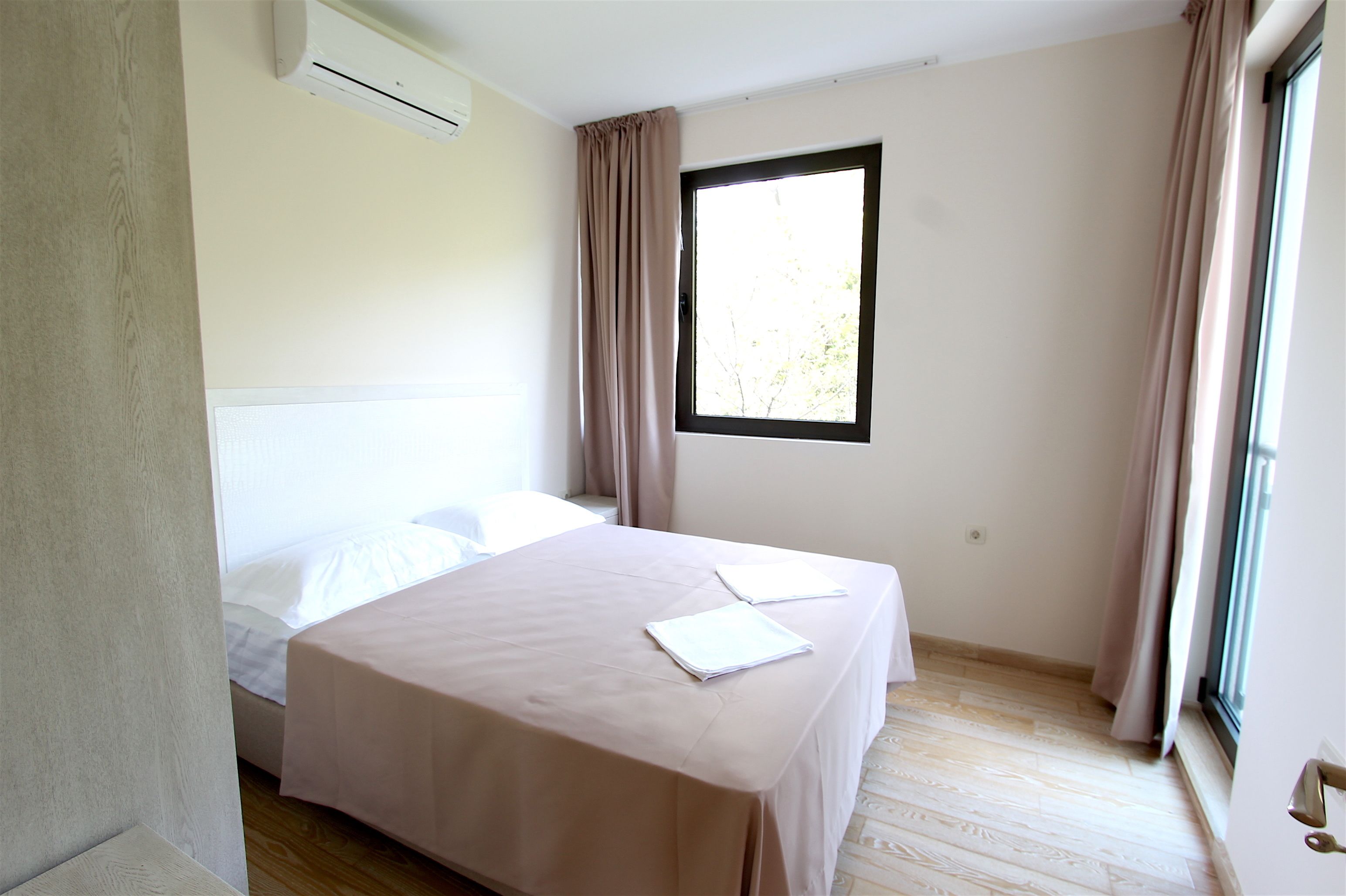 A bedroom with a bed, a window, and an air conditioning unit.