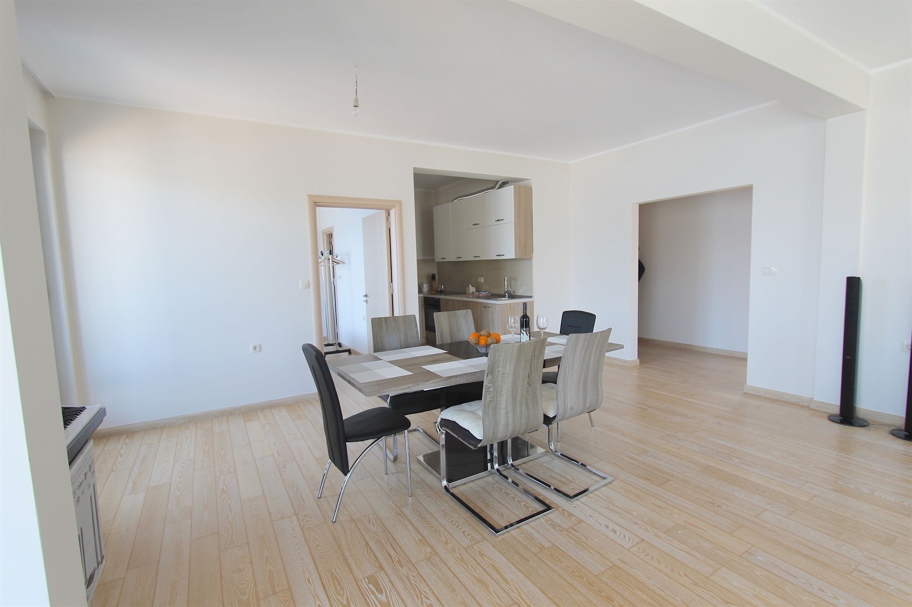Un espace repas moderne avec une table rectangulaire, six chaises et une cuisine en arrière-plan.