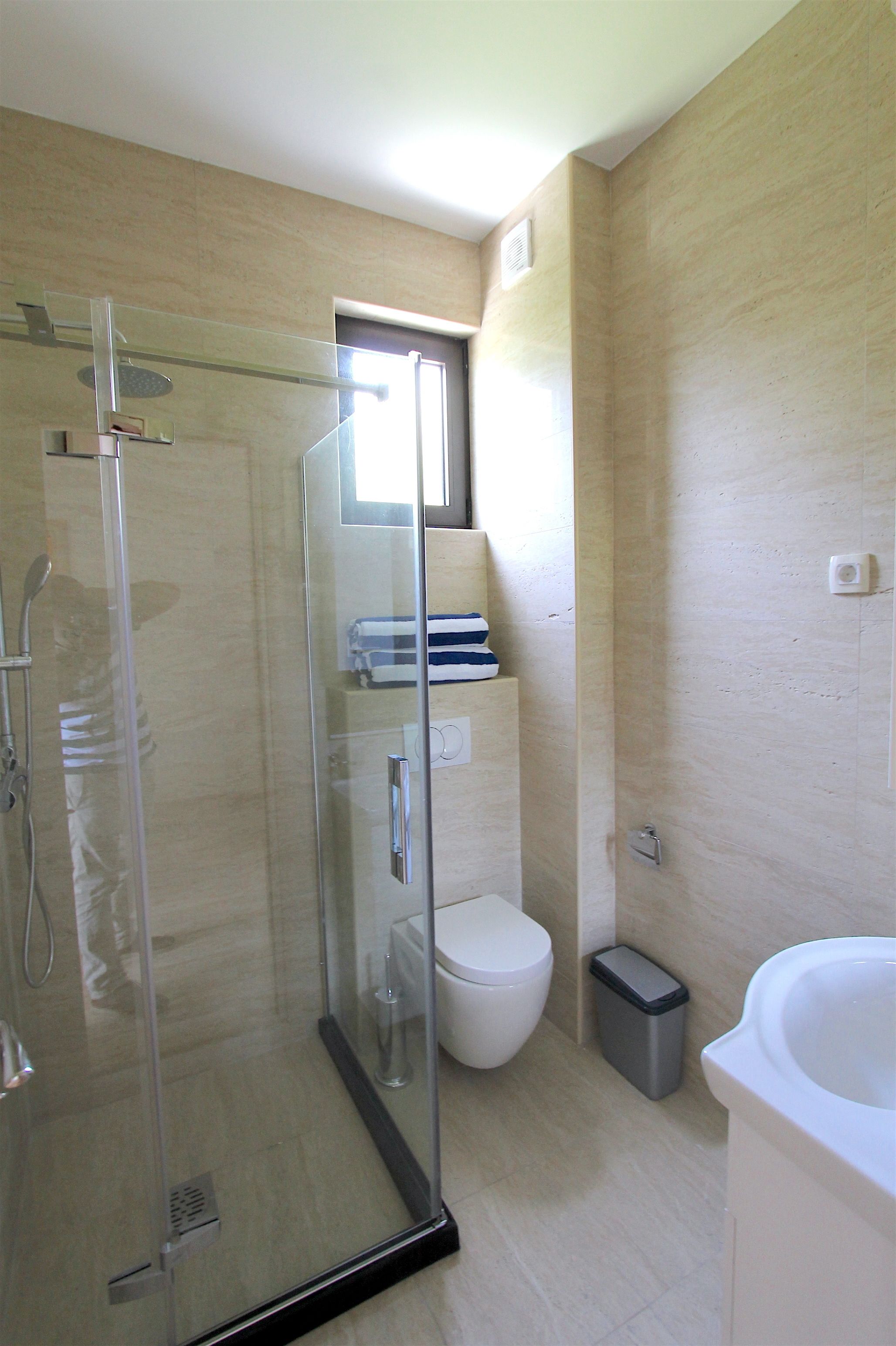 A modern bathroom with a glass-enclosed shower, a toilet, and a bathtub.