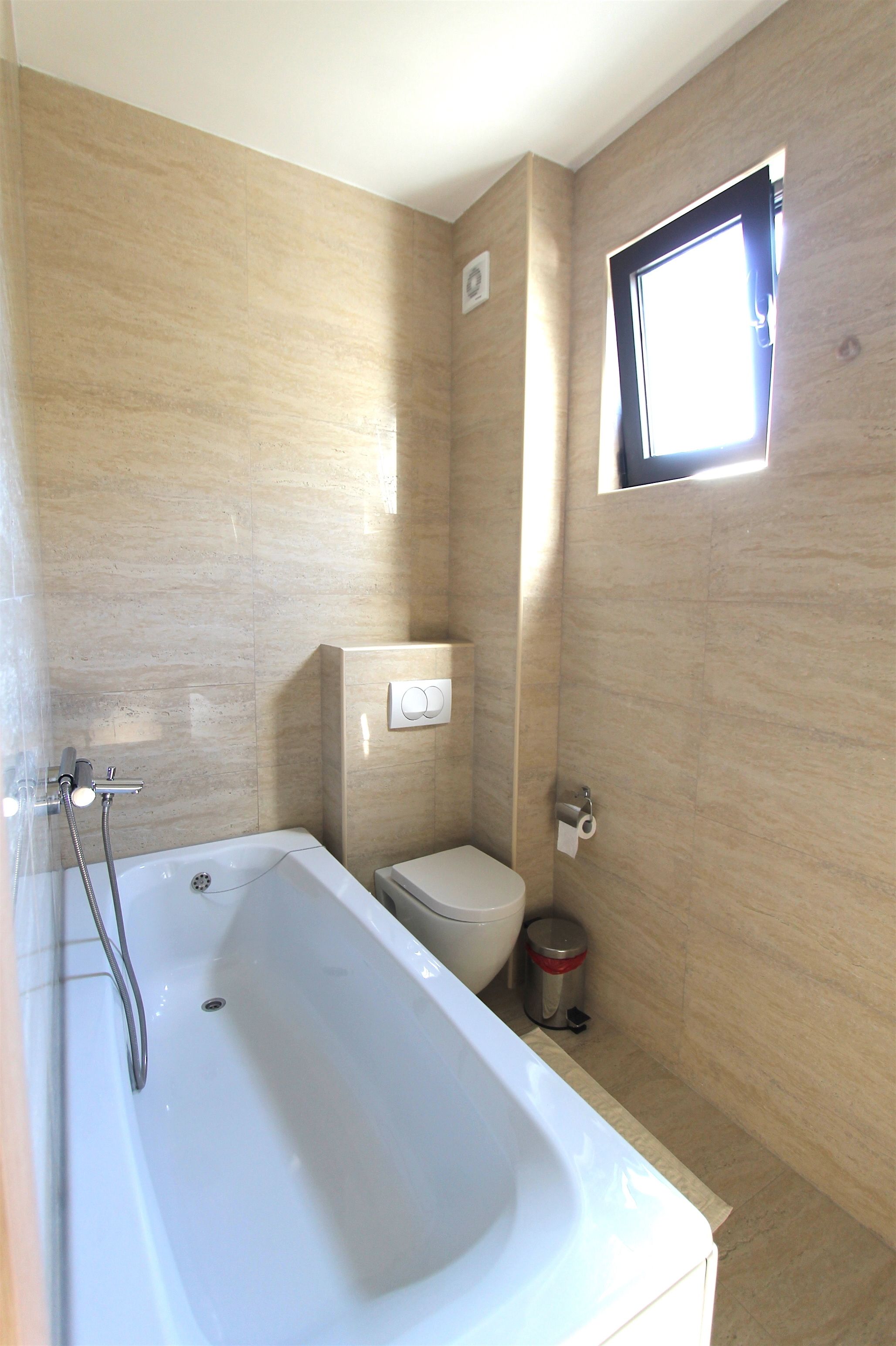 Ein Badezimmer mit einer Badewanne, Toilette und einem kleinen Fenster.