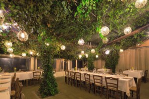 An indoor dining area with tables set for a meal, surrounded by greenery and hanging spherical light fixtures. - La Casa di Campagna (Magione)