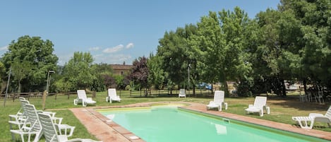 Una piscina al aire libre, sillones reclinables de piscina