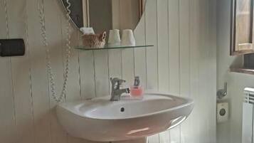 Un baño con lavamanos pedestal, inodoro, bidé y espejo.