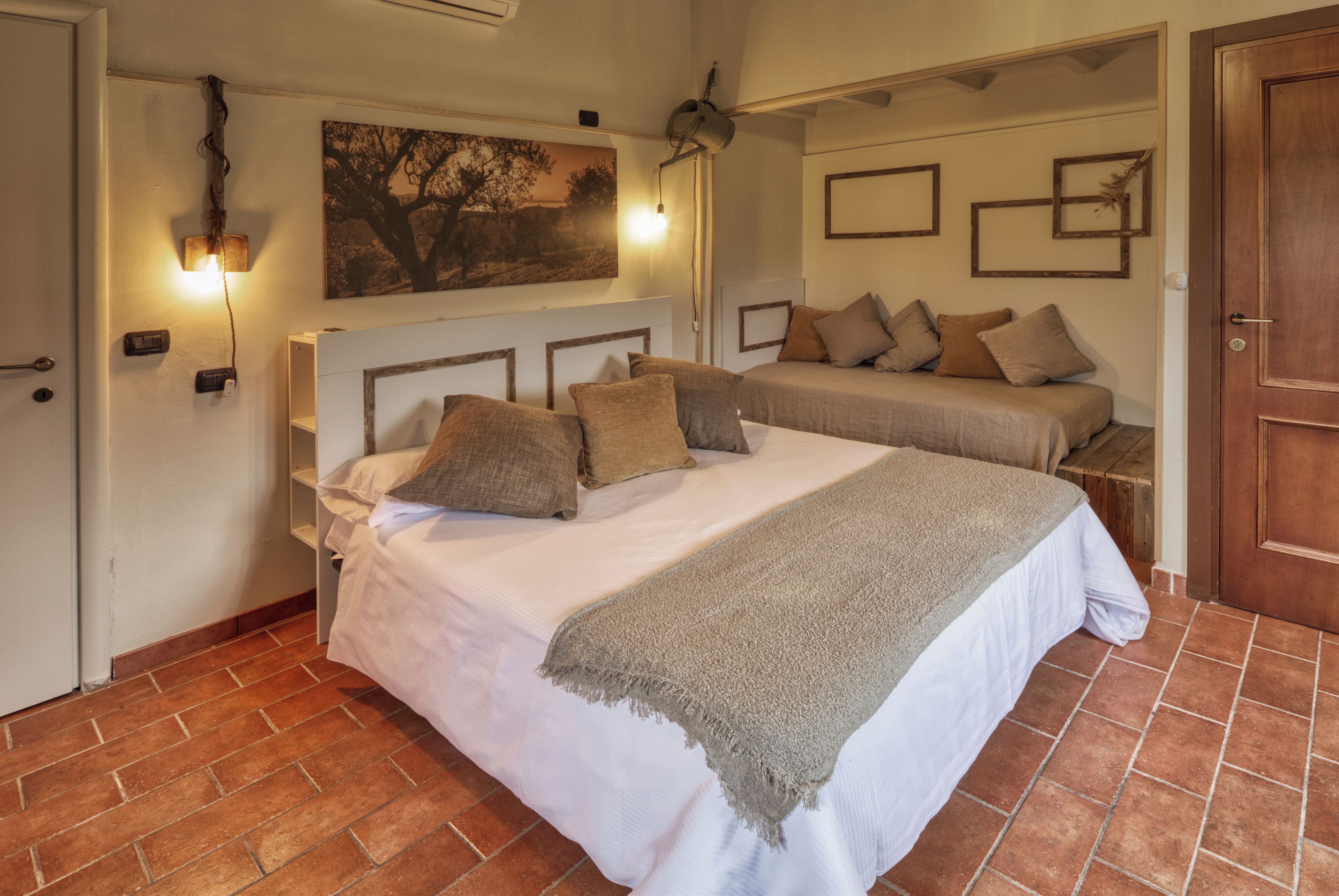 A bedroom with a large bed, a smaller bed, a painting on the wall, and a ceiling fan.