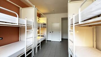 A dormitory room with bunk beds, a door, and a tiled floor.