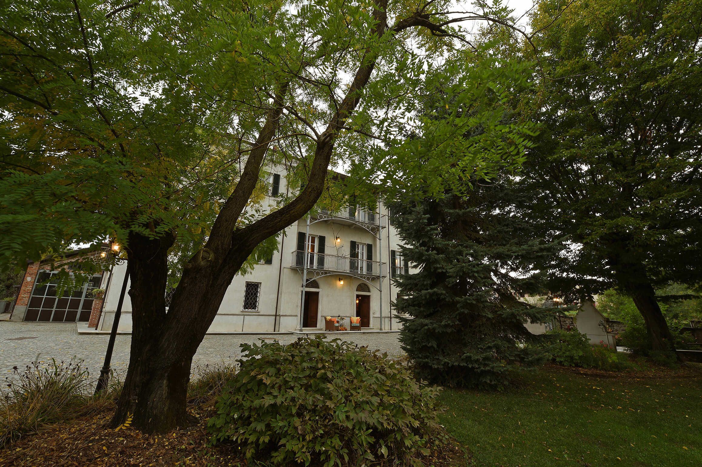 Un bâtiment à deux étages doté d’un balcon, entouré d’arbres et d’une pelouse.