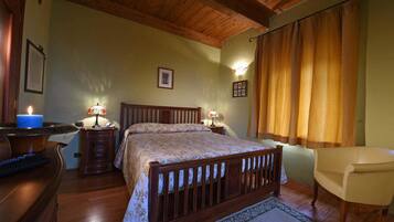 A bedroom with a wooden bed, two bedside lamps, a chair, and a desk with a candle.