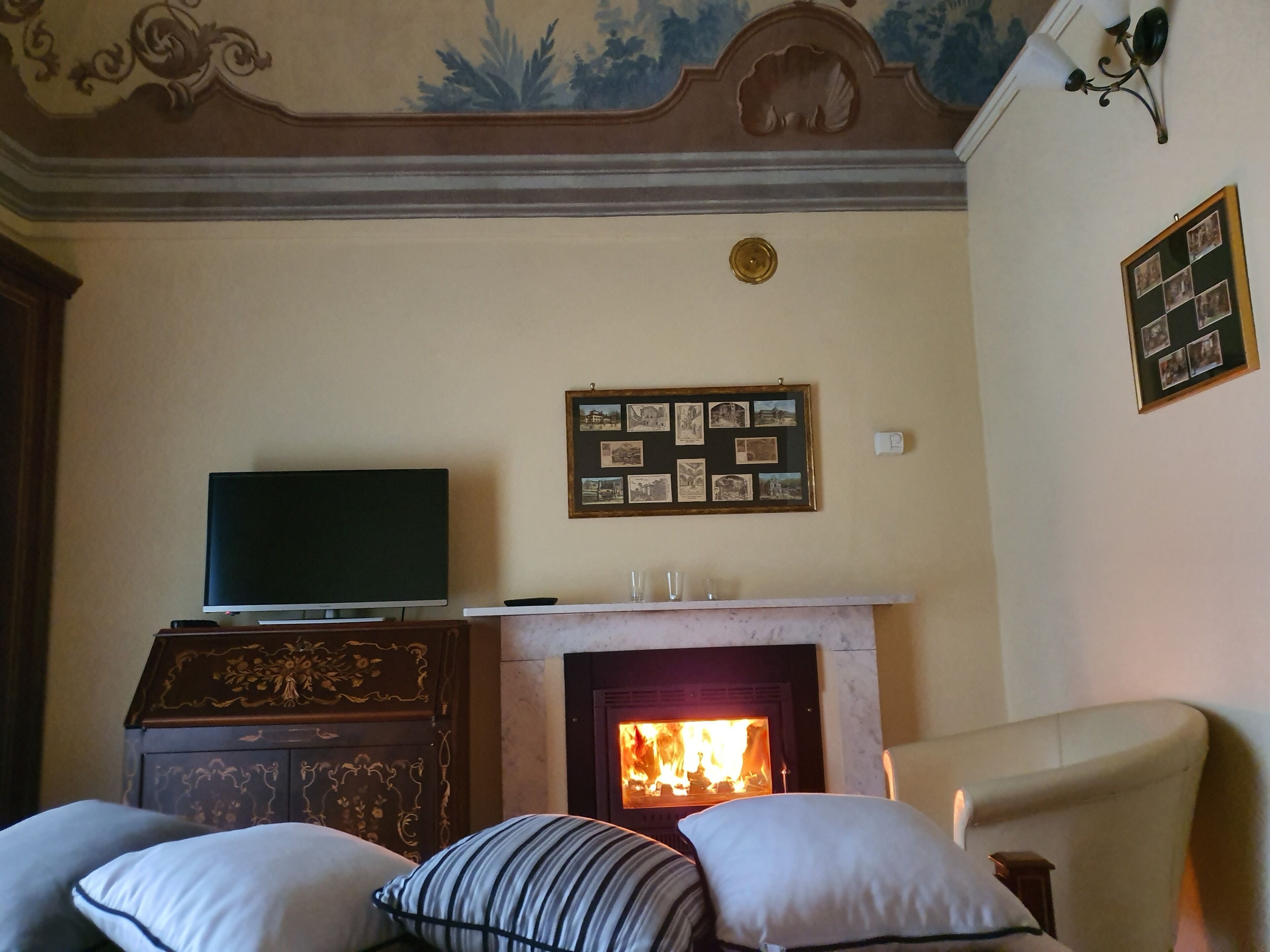Una habitación con chimenea, televisor sobre un mueble de madera y una pared decorada con cuadros.