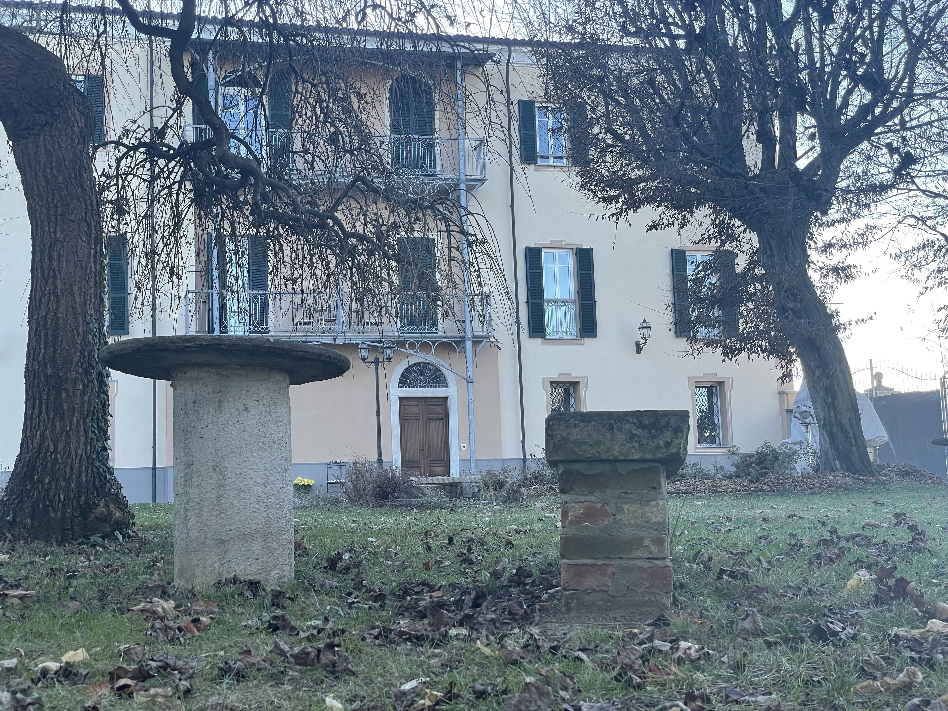 A building with a stone fountain and a stone pillar in the foreground.