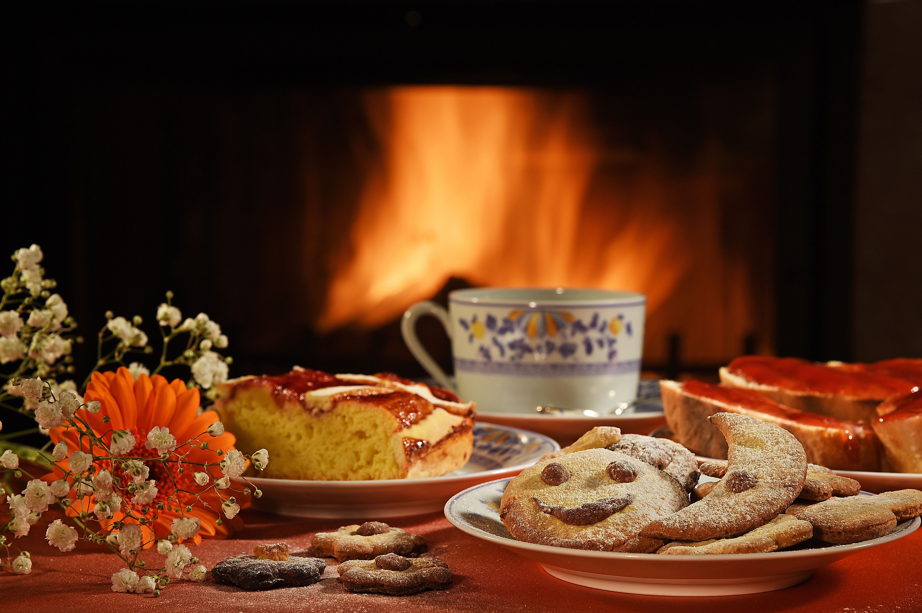 A table with pastries, a cup, and a vase of flowers.