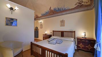 Un dormitorio con una cama de madera, una mesita de noche, una silla y un techo con molduras decorativas.