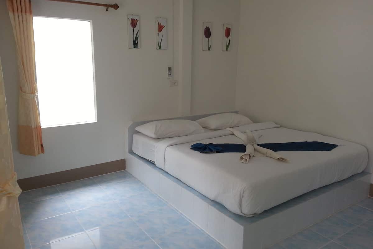 Quarto com cama, janela com cortinas e flores decorativas na parede.