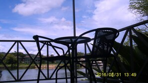 A metal table and chair set overlooking a body of water with a clear sky. - Hadsaisuay Resort (Kanchanaburi)
