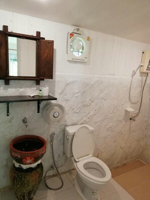 A bathroom with a toilet, a shower, a marble wall, a wooden shelf, and a decorative vase. - Hadsaisuay Resort (Kanchanaburi)