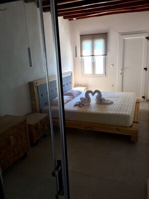Un dormitorio con cama, ventana, puerta y un banco de madera.