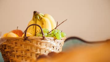 A wicker basket containing bananas, grapes, and an apple.