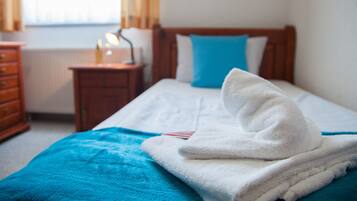 A neatly made bed with a blue blanket and a white towel folded on top.