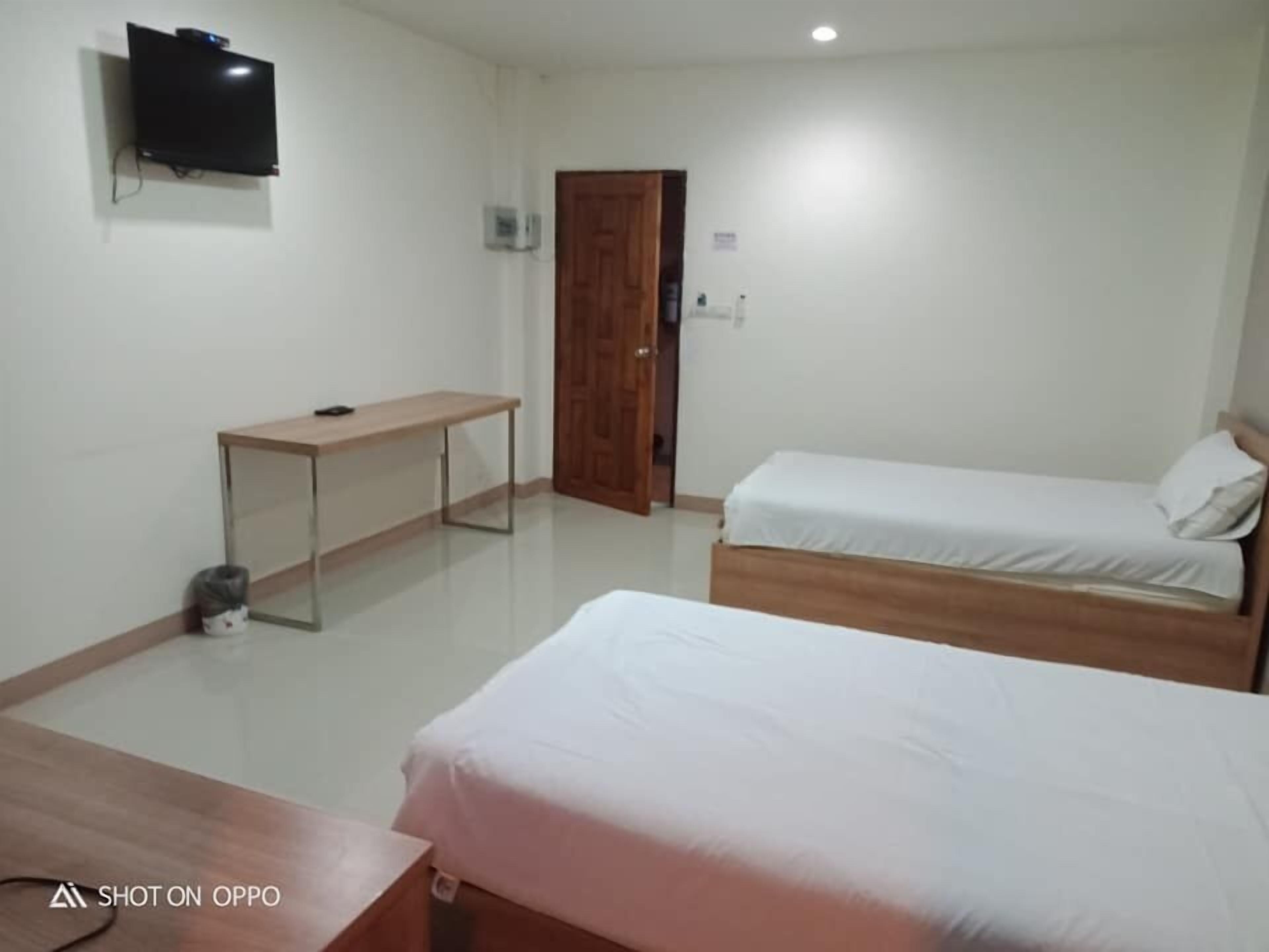 A room with two beds, a desk, a television, and a door.