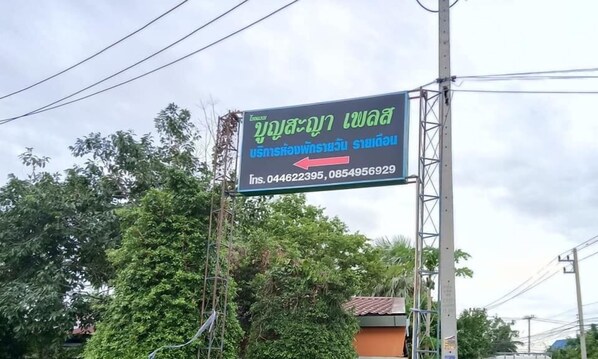 Ein Schild mit thailändischem Text und einer Kontaktnummer.