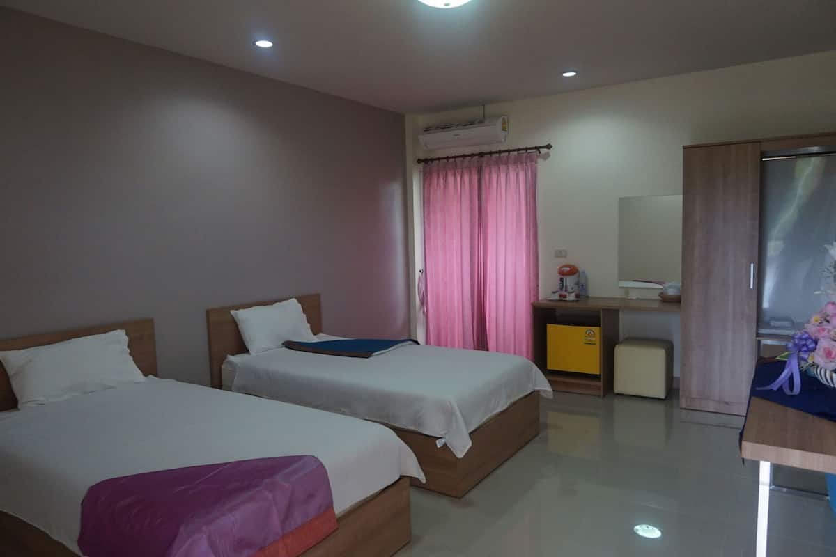 Habitación de hotel con dos camas, un escritorio, un espejo y un armario.