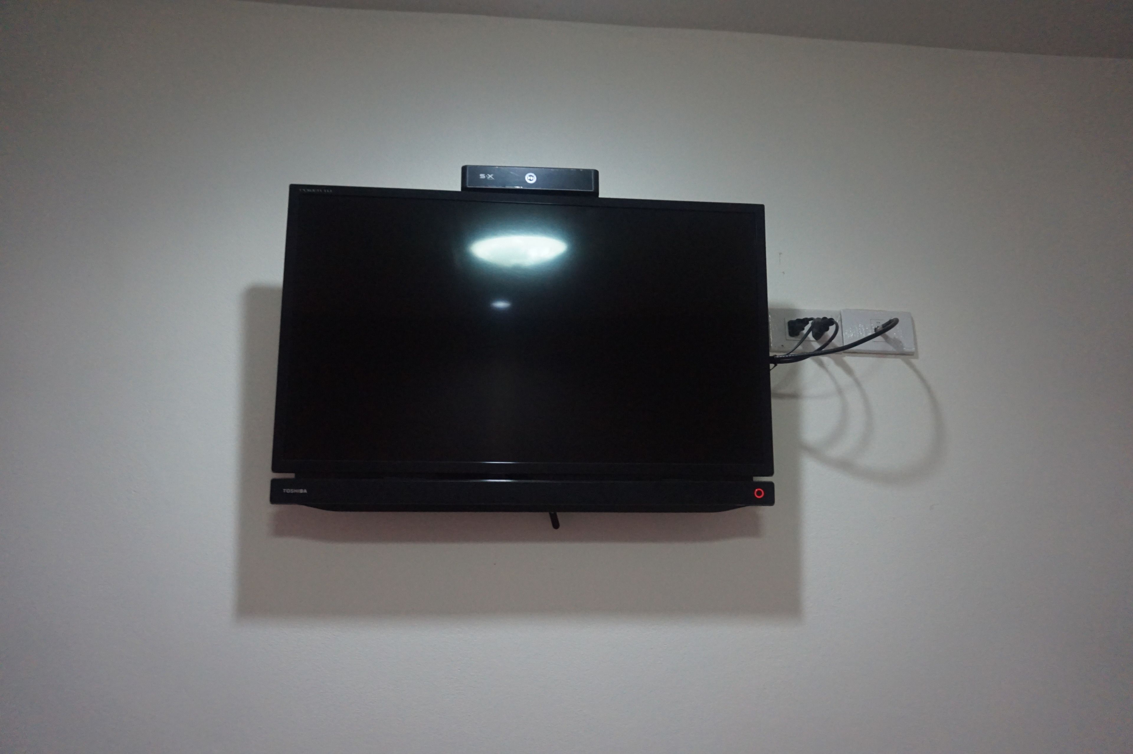Ein Flachbildfernseher an einer schlichten Wand.