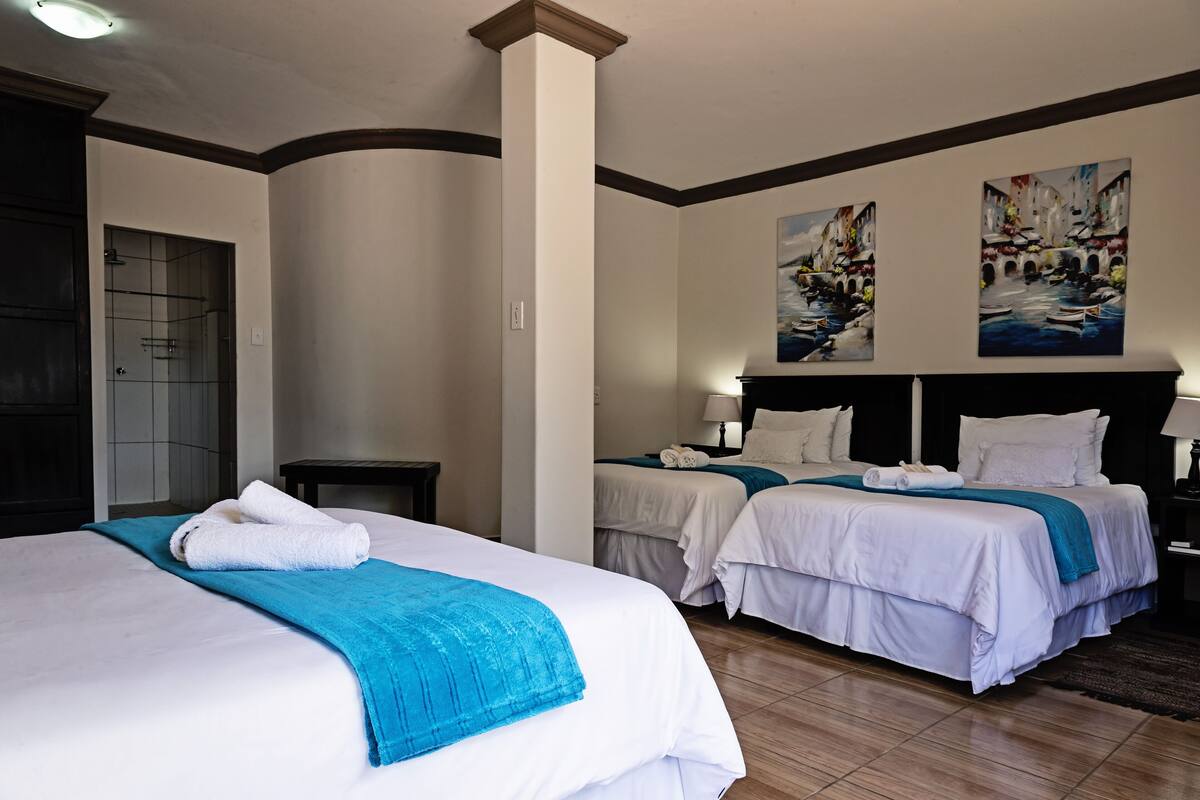A hotel room with two beds, a shower, and artwork on the walls.