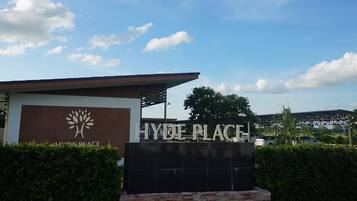 A sign for Hyde Place with a tree logo, surrounded by greenery and a clear sky.