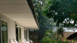 A covered outdoor seating area with lounge chairs and a concrete pathway. - Lipe Village Resort (Koh Lipe)